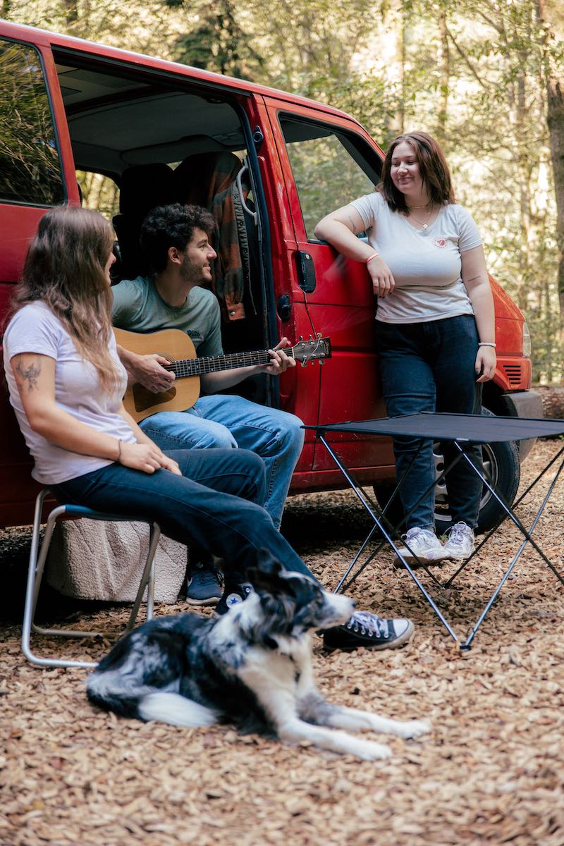 Menschen spielen Gitarre vor einem Camper-Van
